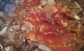 Луковые кусочки высыпаем к мясу и обжариваем 10 минут. Далее заливаем ингредиенты томатным «соком» и посыпаем приправами.