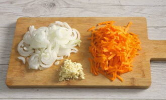 Как приготовить классическую солянку из капусты на сковороде? Натираем на крупной терке морковь. Репчатый лук нарезаем тонкими полукольцами. Зубчики чеснока измельчаем любым удобным способом. Количество чеснока регулируем по вкусу.