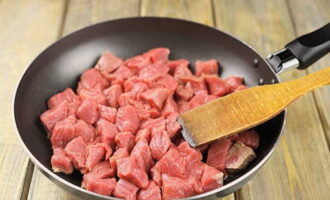 Как приготовить классический гуляш из говядины с подливкой на сковороде? Хорошо промываем говядину и нарезаем ее небольшими равными кусочками. Выкладываем мясо на сковороду с растительным маслом.