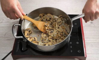Разогреваем глубокую сковороду с растительным маслом. Выкладываем сюда грибы, которые режем тонкими пластинками. Жарим 10 минут. После добавляем лук. Перемешиваем продукты и готовим еще около 6 минут.