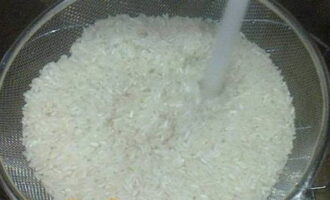 Промойте рисовую крупу проточной водой. Противень с высокими бортами смажьте растительным маслом и выложите на него рисовую крупу, немного посолите ее.