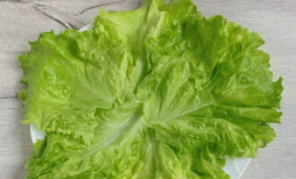 Дно плоского блюда выстилаем промытыми листьями зеленого салата.