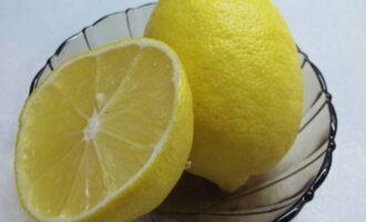 Лимон промываем под водой и разрезаем на две половинки.