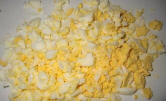 Отварные яйца очищаем от скорлупы и некрупно нарезаем (примерно так же, как и крабовые палочки). Отправляем к остальным продуктам.