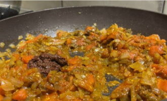 В сковороду вливаем растительное масло и нагреваем 2-3 минуты, пассеруем лук и высыпаем томаты, прогреваем еще пару минут и вводим паприку, хмели-сунели, аджику и хорошенько перемешиваем.