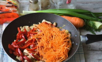 Дополняем курицу морковью и болгарским перцем. Размешиваем содержимое сковороды и готовим еще 15 минут.
