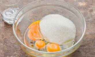 В глубокую вместительную емкость отправляем три куриных яйца и присоединяем к ним сахарный песок.
