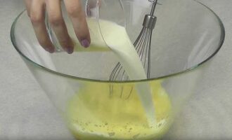 К яичной массе налить один стакан (200 мл) немного подогретого молока и перемешать.