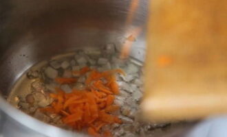 Поставьте на плиту кастрюлю с толстым дном, налейте в нее немного растительного масла. Сначала обжарьте до легкого золотистого цвета лук и морковку.
