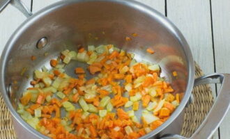 Прямо в кастрюле прогреваем подсолнечное масло и обжариваем на нем кубики моркови и лука. Жарим их около двух минут, регулярно размешивая.