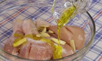 В посуду к подготовленным куриным голеням добавляем нарезанный чеснок, а также соль (регулируем по вкусу) и вливаем оливковое масло.
