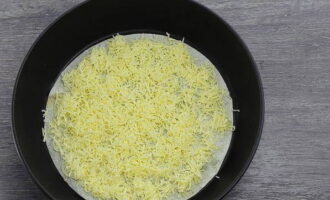 Твердый сыр натираем на терке со средними отверстиями и половиной сырной стружки присыпаем основу из лаваша.