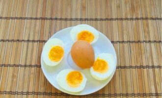 Параллельно отвариваем яйца так, чтобы желток оставался слегка жидковатым. Остужаем, очищаем и разрезаем пополам.