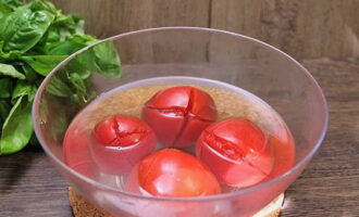 На промытых помидорах делаем крестообразные надрезы и обдаем крутым кипятком. Спустя 5 минут ополаскиваем под холодной водой и снимаем кожицу.