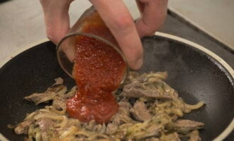 В сковороду добавляем соленые огурцы, в спустя 2-3 минуты – томатный соус. Блюдо солим и перчим, убавляем нагрев и томим до готовности мяса.