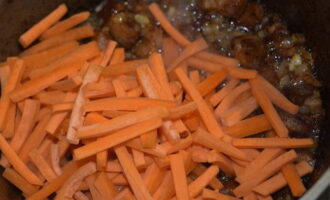 Добавляем морковь и спустя 3-4 минуты засыпаем зиру и молотый перец, продолжаем жарку еще 5-6 минут.