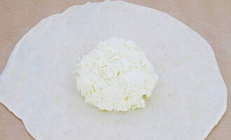 Тесто делим пополам и раскатываем в круглые лепешки, в центр каждый заготовки выкладываем сырный шарик.